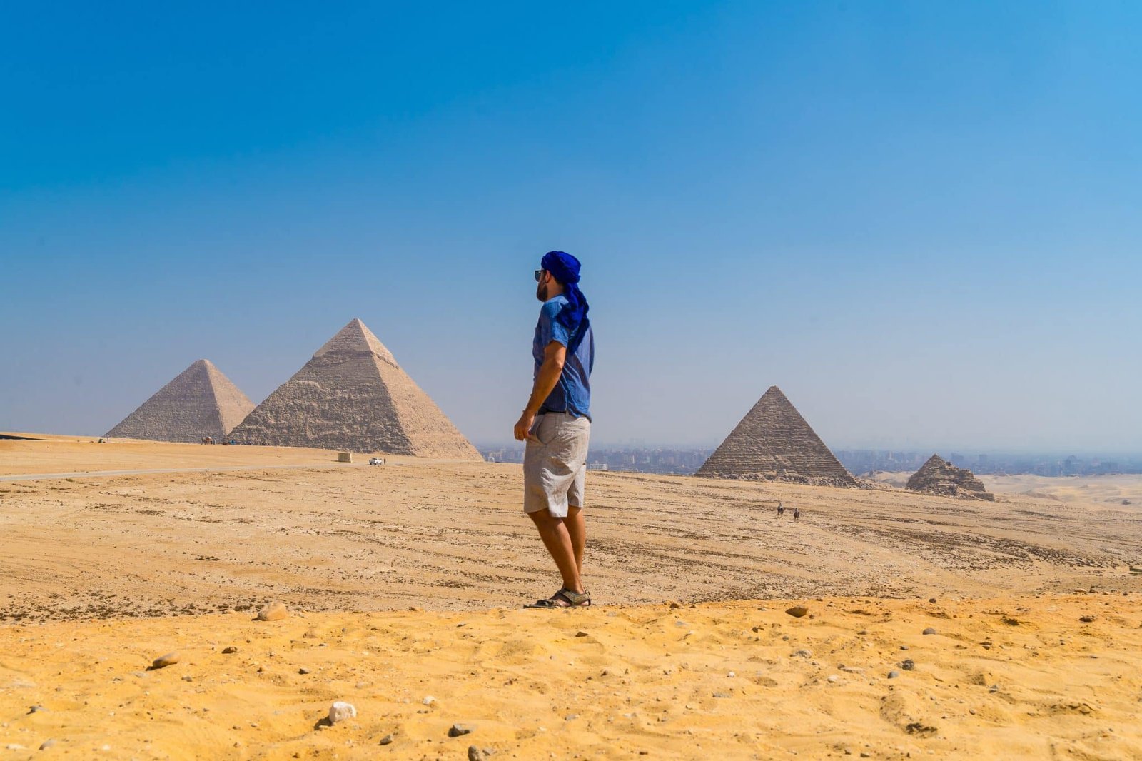Portrait of a young man in a blue turban walking next to the Pyramids of Giza, Cairo, Egypt