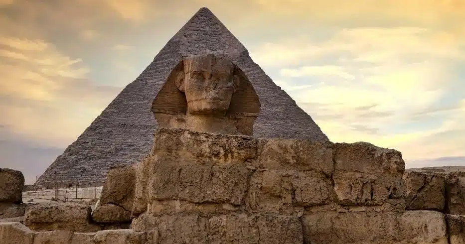 Great Sphinx in front of a Giza pyramid at sunset